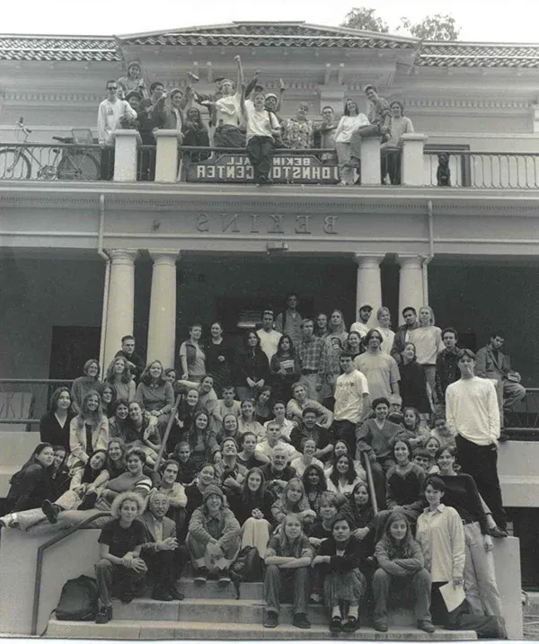 A group of students stands in front of Bekins Hall with a sign that says Johnston Center