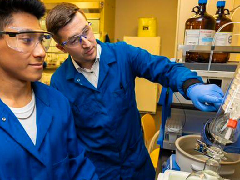 Professor teaching student in research science lab.